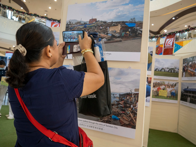 Shoppers stop to look at the pictures, recalling perhaps their own painful memories of the Category 5 storm.  【Photo by Matt Serrano】