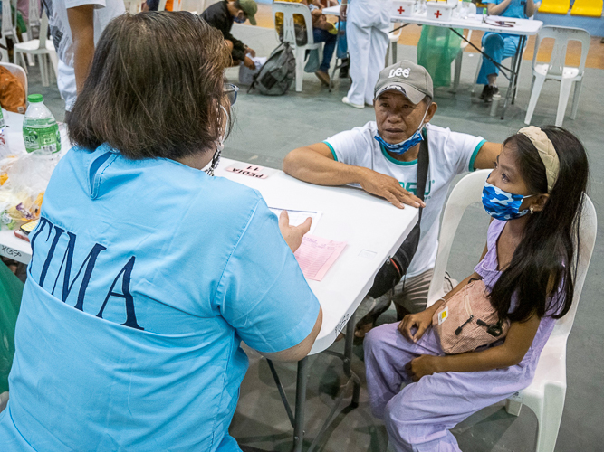 A young patient with her guardian consults the Tzu Chi volunteer doctor. 【Photo by Matt Serrano】