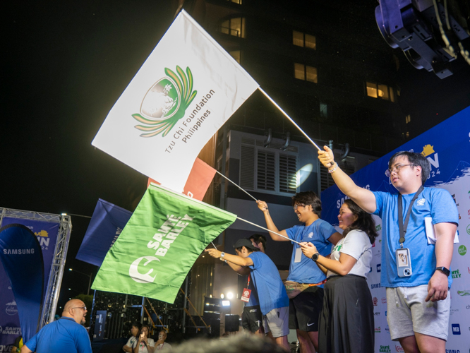 A co-race organizer waves the flag of Tzu Chi Foundation Philippines, the advocacy partner of Galaxy Watch Earth Day Run by Runrio. 【Photo by Matt Serrano】