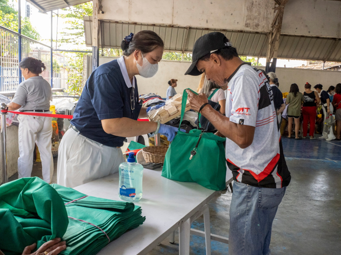 Done with his shopping, a man shows his choices to a Tzu Chi volunteer at the bazaar’s check-out area. 【Photo by Matt Serrano】