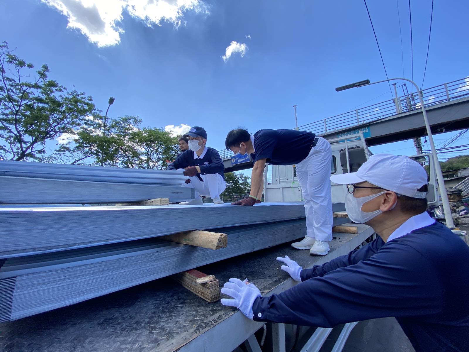 Volunteers tolerate the sweltering heat on April 2 as they unload galvanized iron (GI) sheets for distribution. Four sheets were given to each of the 625 families that lost their home to a fire in Barangay 105, Tondo, Manila, last March 21.