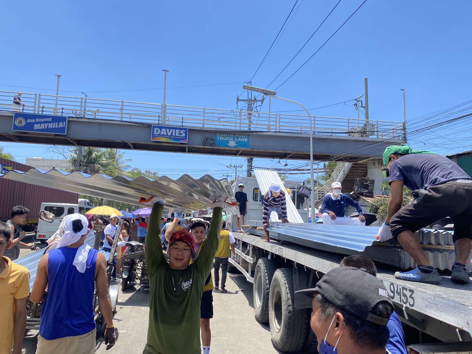 Volunteers tolerate the sweltering heat on April 2 as they unload galvanized iron (GI) sheets for distribution. Four sheets were given to each of the 625 families that lost their home to a fire in Barangay 105, Tondo, Manila, last March 21. 