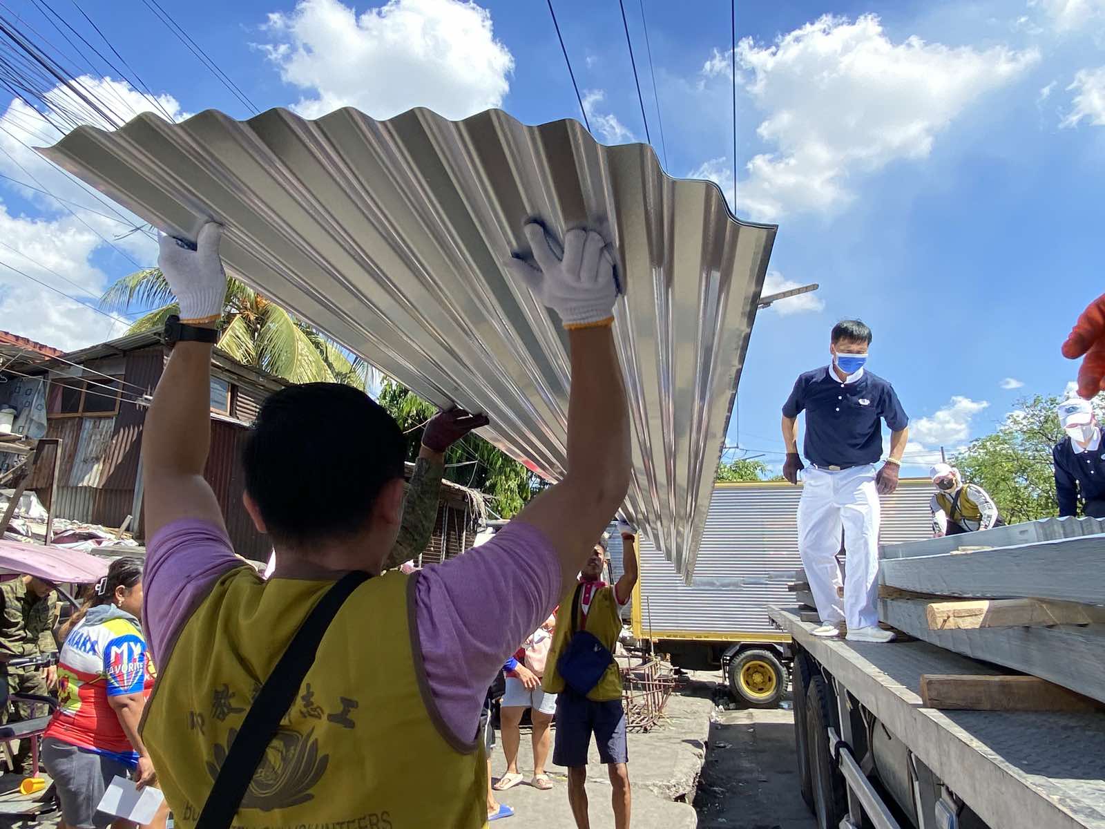 Volunteers tolerate the sweltering heat on April 2 as they unload galvanized iron (GI) sheets for distribution. Four sheets were given to each of the 625 families that lost their home to a fire in Barangay 105, Tondo, Manila, last March 21.