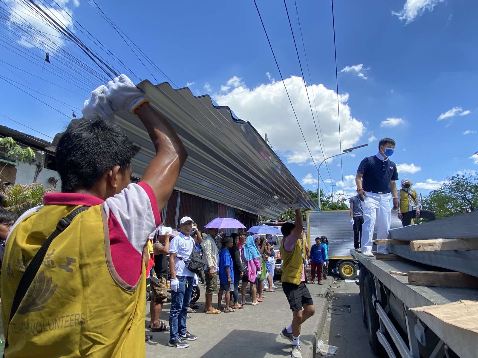 Volunteers tolerate the sweltering heat on April 2 as they unload galvanized iron (GI) sheets for distribution. Four sheets were given to each of the 625 families that lost their home to a fire in Barangay 105, Tondo, Manila, last March 21.