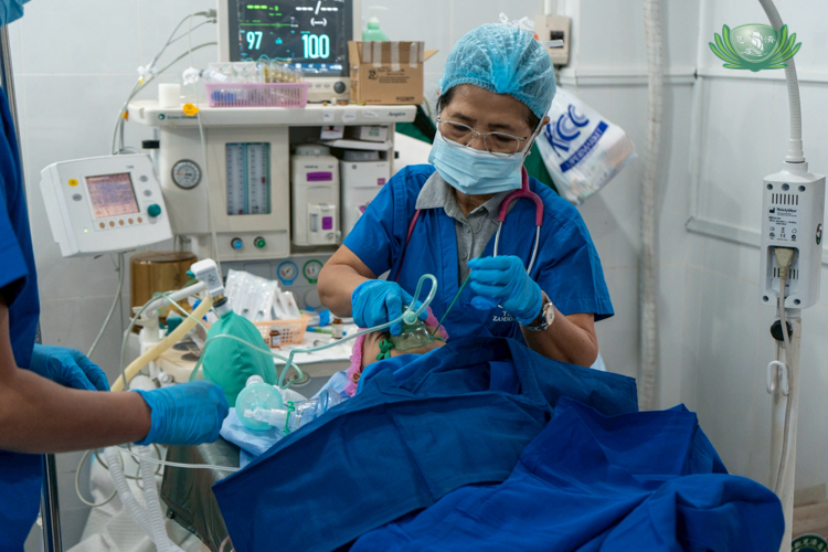 A volunteer doctor monitors the patient’s vital signs during surgery.