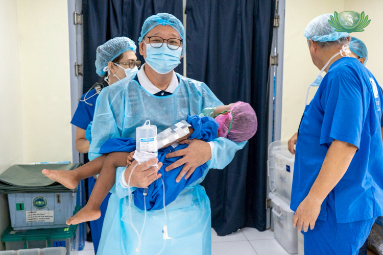 Tzu Chi Zamboanga OIC and Deputy CEO Dr. Anton Mari Lim carries patient Sab Harvey, son of April Mae Lacastesantos.