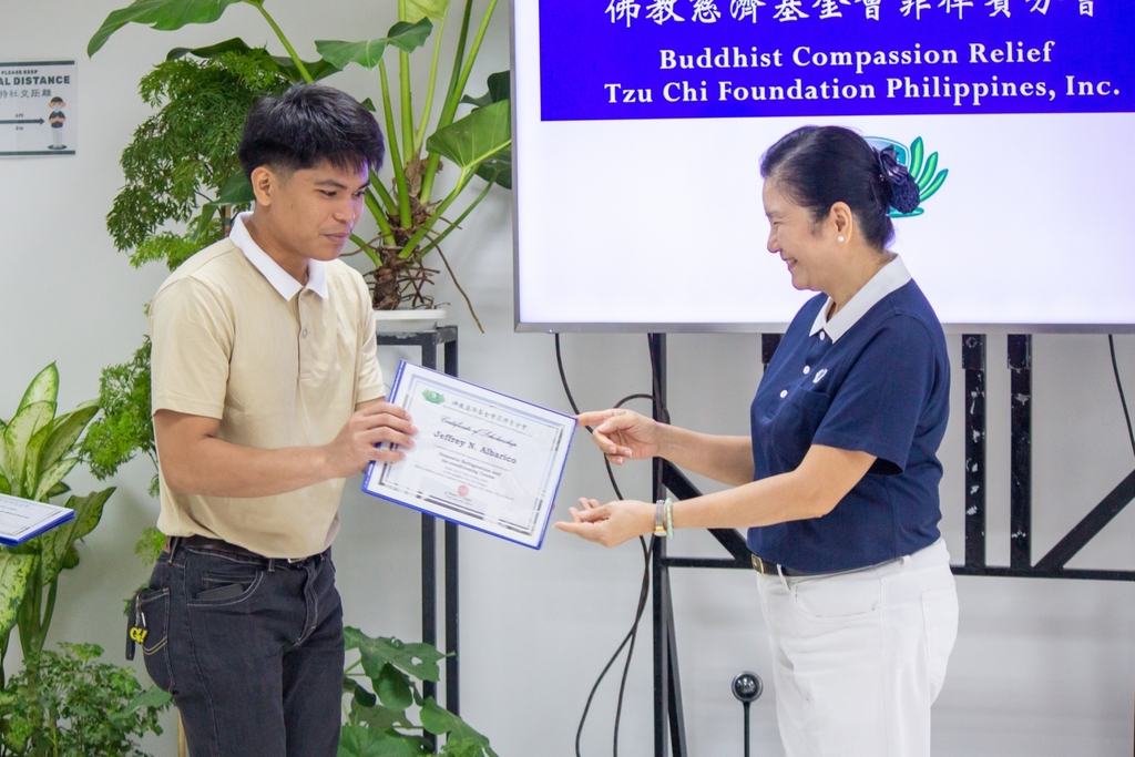 Then 23-year-old Jeffery Albarico (left) receives his certificate from Tzu Chi Education Committee Head Rosa So.