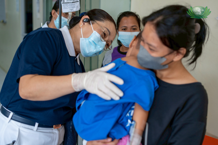A Tzu Chi volunteer tries to comfort a young patient.