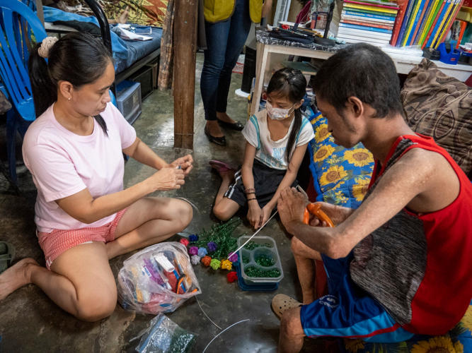 Princess (center) and Jasper (right) help their mother Jocelyn assemble her orders of acrylic flowers. 【Photo by Matt Serrano】