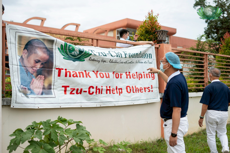 Tzu Chi volunteers help set up a signage of Dharma Master Cheng Yen, thanking patients for their participation in the 283rd medical mission.