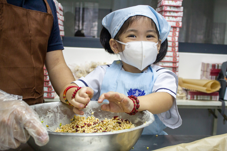 Preschool student enjoys mixing ingredients for the pistachio cranberry chocolate bark during the bake sale. 【Photo by Matt Serrano】
