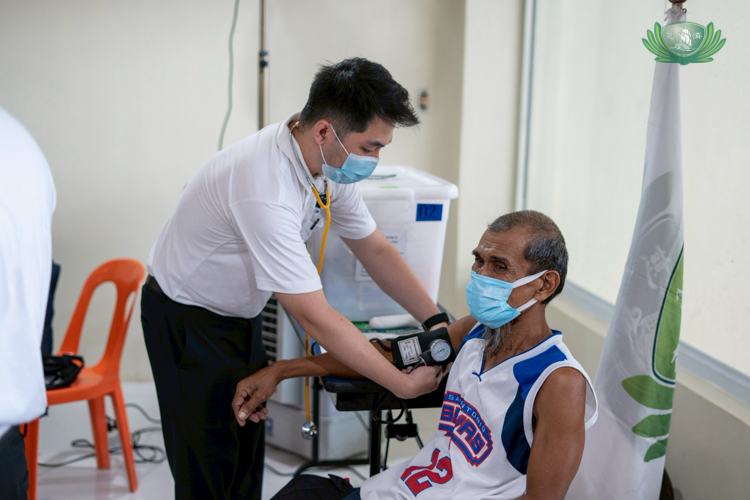A volunteer nurse helps assess the patient’s vital signs.
