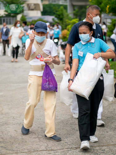 A Tzu Chi scholar helps a volunteer carry his bag of assorted groceries.【Photo by Daniel Lazar】
