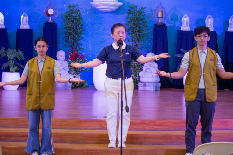 Flanked by Humanity class hosts Margo Janelle Ma-Ang (first from left) and Jefferson Aguilar (first from right), Tzu Chi volunteer Emy Tan demonstrates the sign language for the song “One Family.”