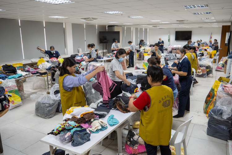 Volunteers work in different stations sorting clothes of the same kind and packing them as a set.