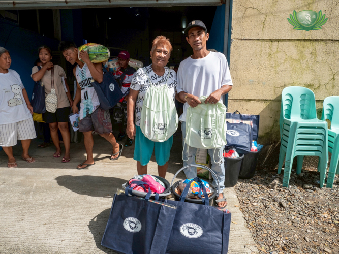 Linda Danao (left) and her son Harriz now have two bags from Tzu Chi. The green bags are from the relief efforts of Typhoon Karding in 2022, and the blue bags are from relief distribution for Typhoon Uwan.