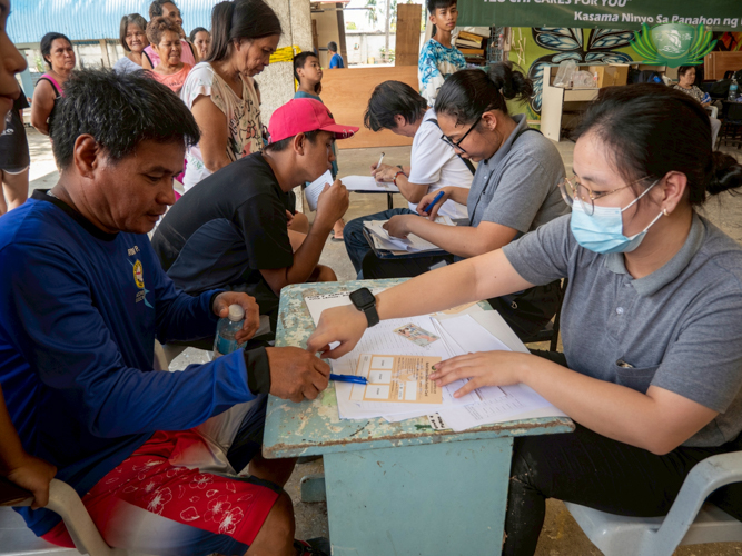 Tzu Chi staff patiently assist beneficiaries in double-checking the master lists during the relief operation.