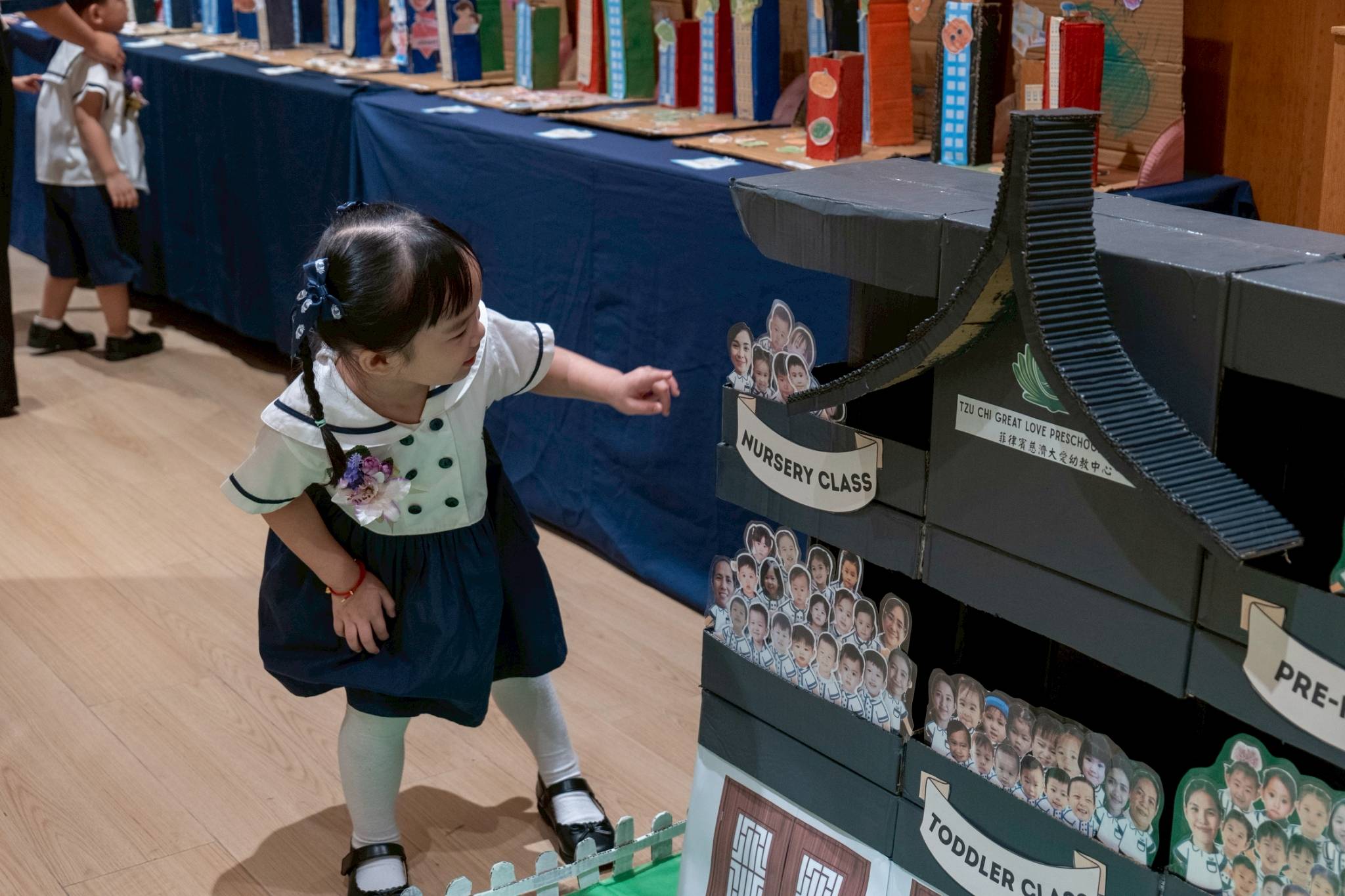 A nursery student looks for her photo in a carboard cutout of Tzu Chi Great Love Preschool Philippines. 