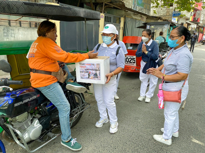 A tricycle driver drops money into Tzu Chi’s donation box for Turkey and Syria. 【Photo by Matt Serrano】