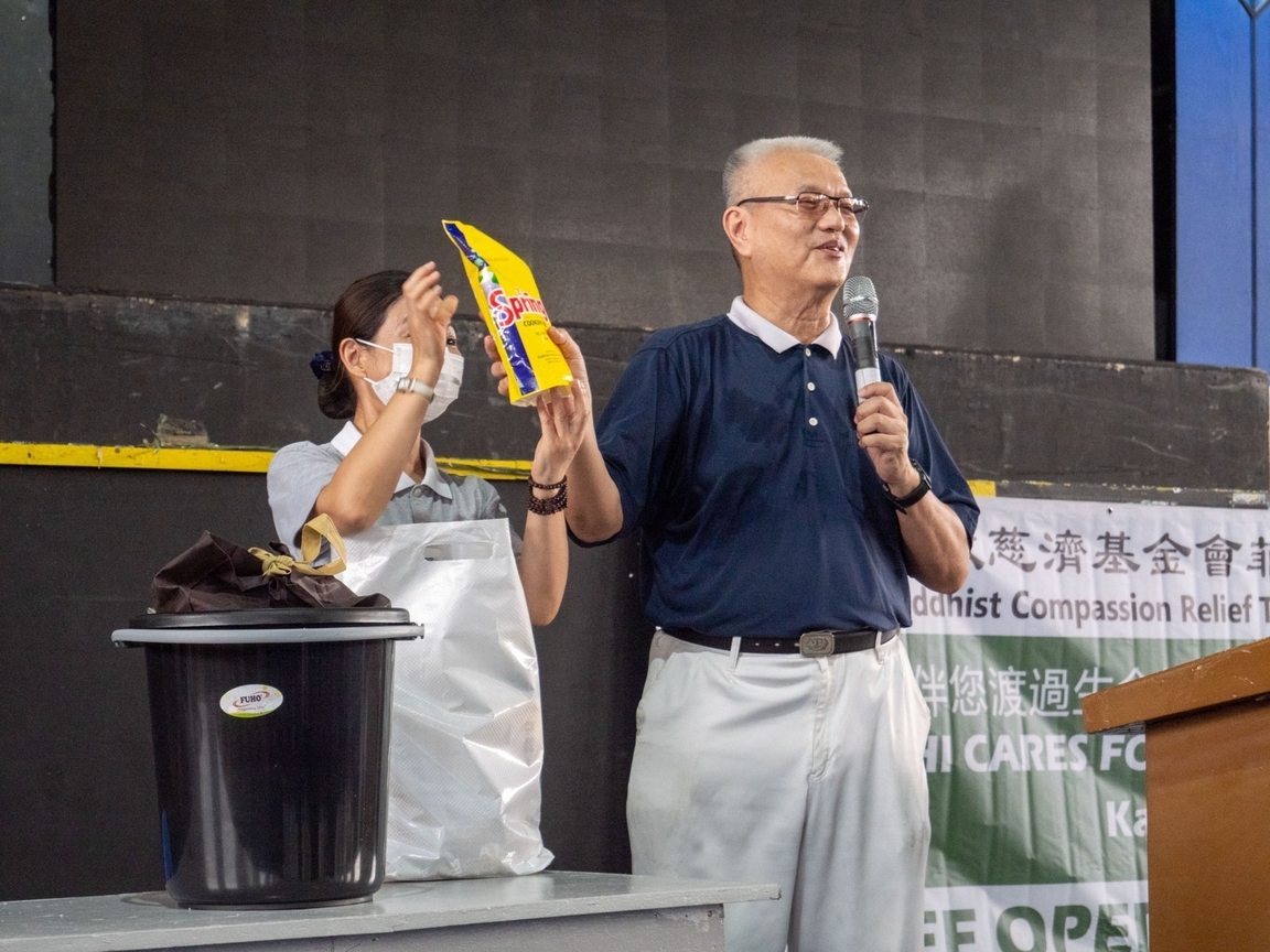 Tzu Chi volunteer Lino Sy (right) shows beneficiaries the items they will receive, such as essential cooking items.