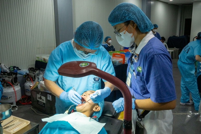 A volunteer dentist (left) and Tzu Chi Youth Volunteer from Taiwan (right) work hand-in-hand for the tooth fillings.