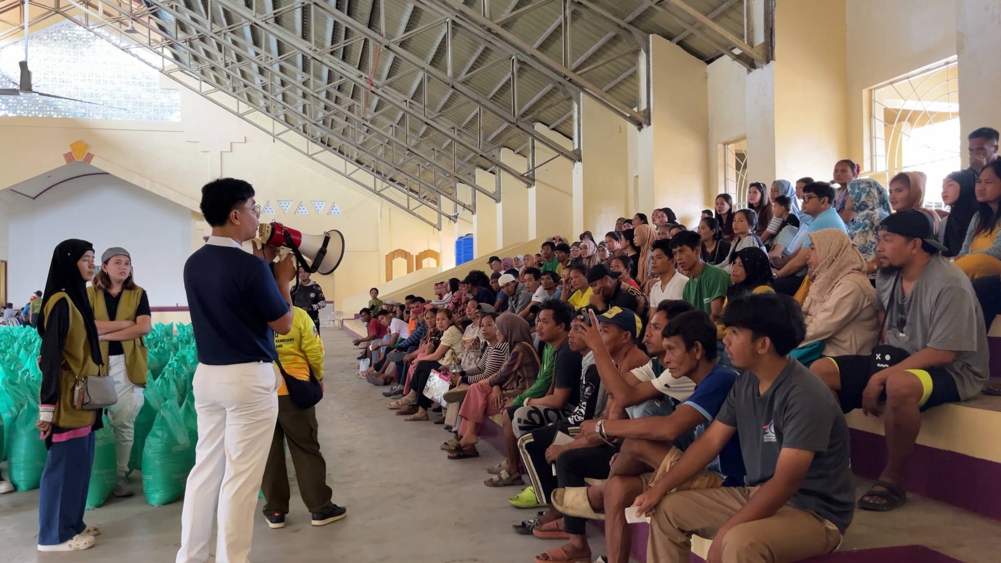 Tzu Chi volunteer Dhing Abdulaup  provides instructions on the process of claiming rice relief. 