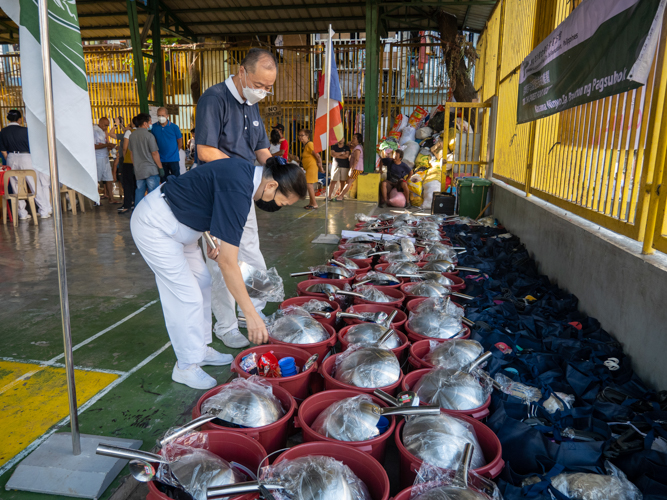 Volunteers set up relief goods for fire victims. Rice, kitchen and personal care essentials, and a grocery gift check were given to representatives of the 51 families affected by the blaze. 【Photo by Matt Serrano】