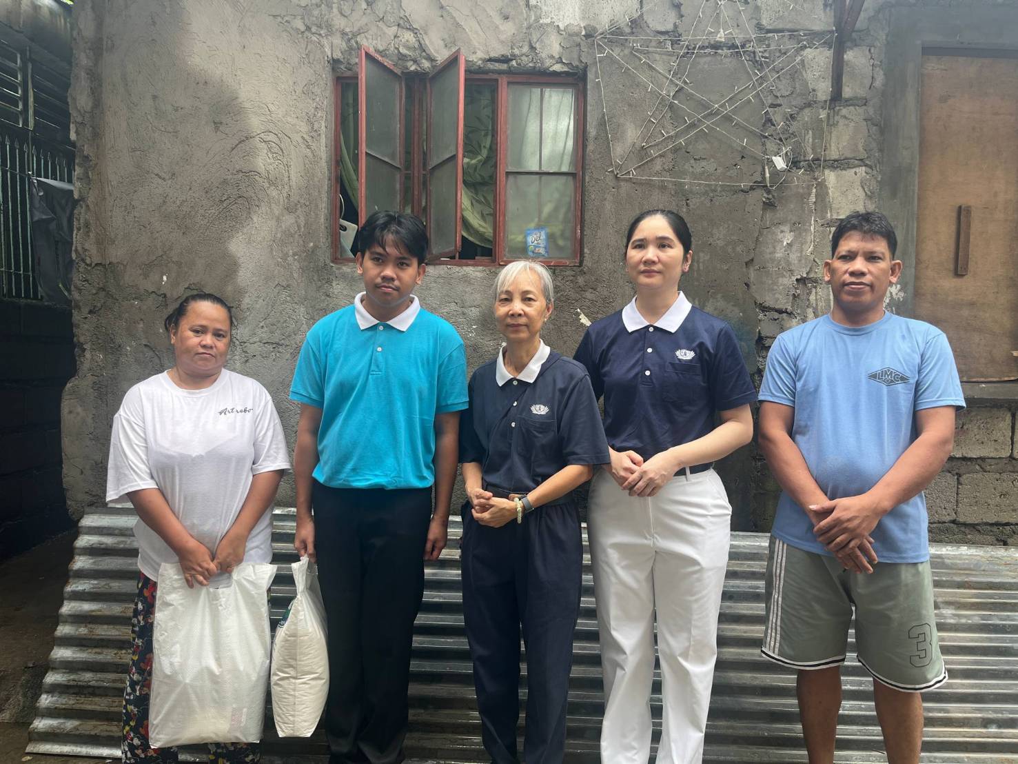 In Valenzuela, Tzu Chi scholar Rhenz Malijan (second from left) and family received a 10k sack of rice, groceries, and two GI sheets.