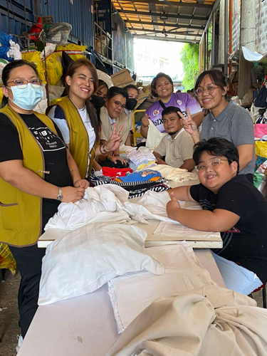Tzu Chi Technical Vocational scholars and happy volunteers pose for a photo while folding the donated pillowcases.
