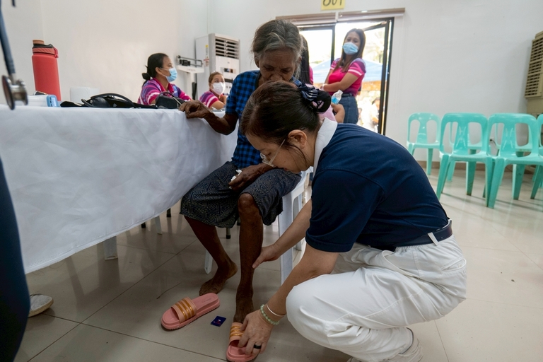 Tzu Chi volunteer Winnie Yu gives 74-year-old beneficiary Carmila Bato-Bato a new pair of slippers, adding a bit of comfort for her bare feet.
