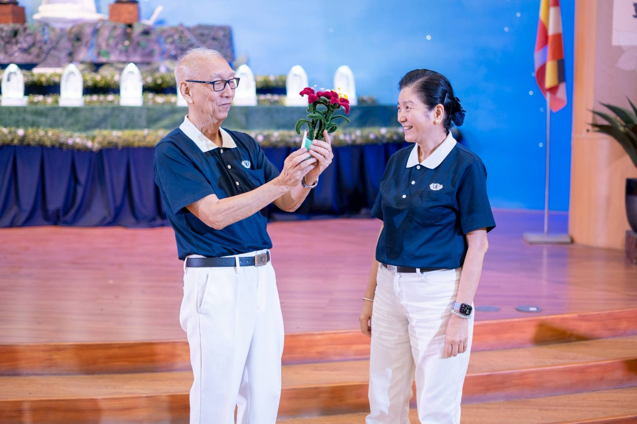 Tzu Chi Education Committee Head Rosa So (right) presented Humanities class speaker Edward So with a flower décor handmade from fuzzy wire by Tzu Chi scholars. 