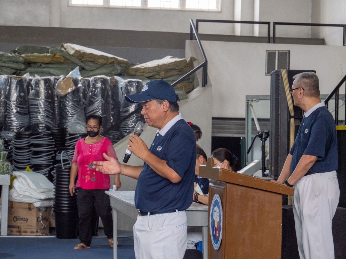 Tzu Chi volunteer Johnny Kwok (in cap) explains how to use the gift vouchers.