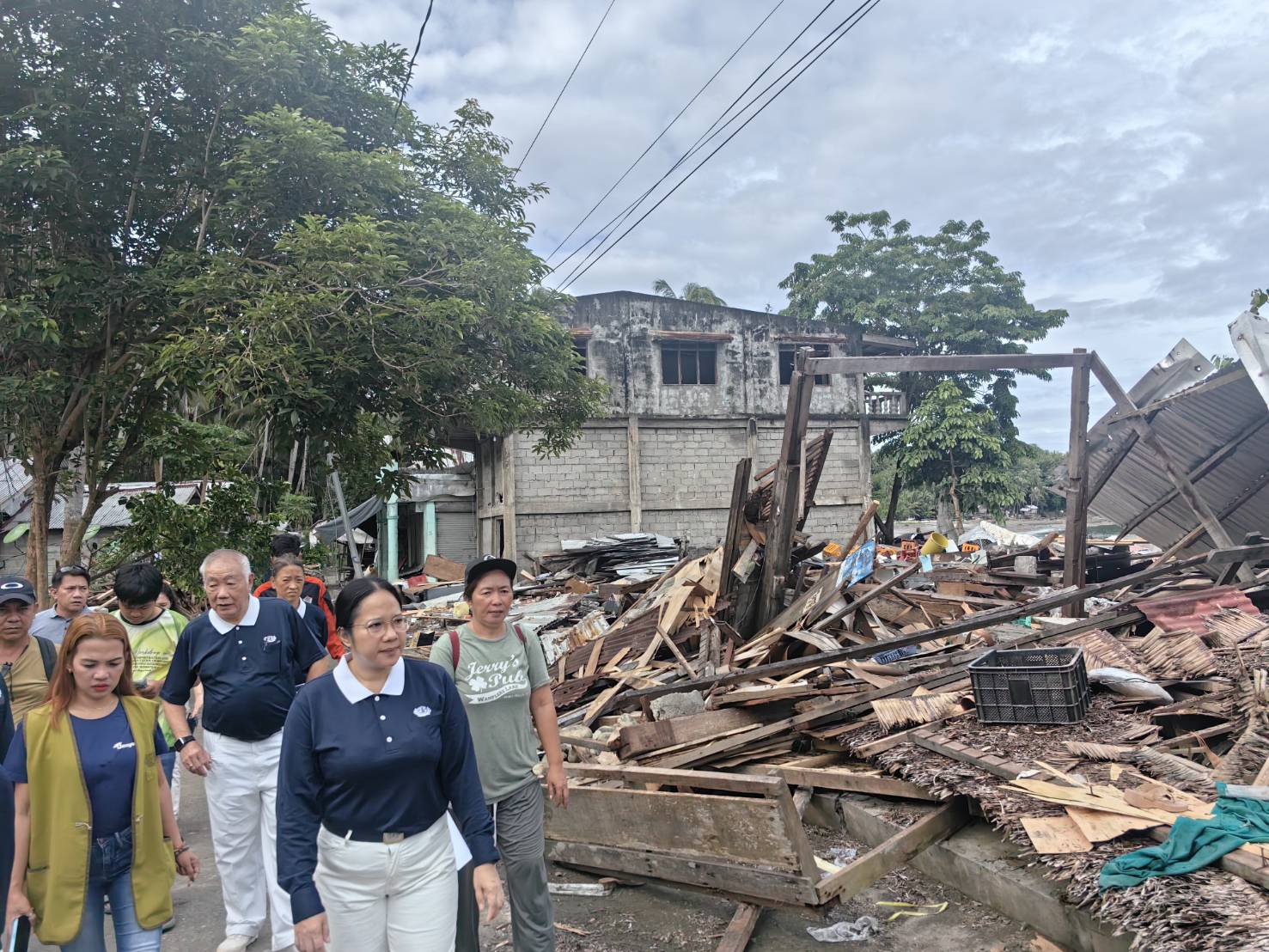 Volunteers walk past a pile of debris where a house once stood. 