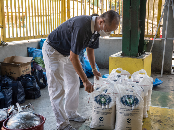 Volunteers set up relief goods for fire victims. Rice, kitchen and personal care essentials, and a grocery gift check were given to representatives of the 51 families affected by the blaze. 【Photo by Matt Serrano】