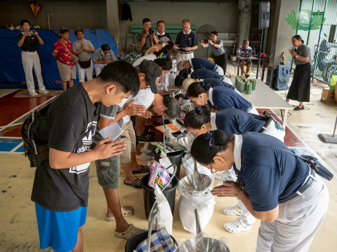 Volunteers and beneficiaries exchange bows during the relief distribution.