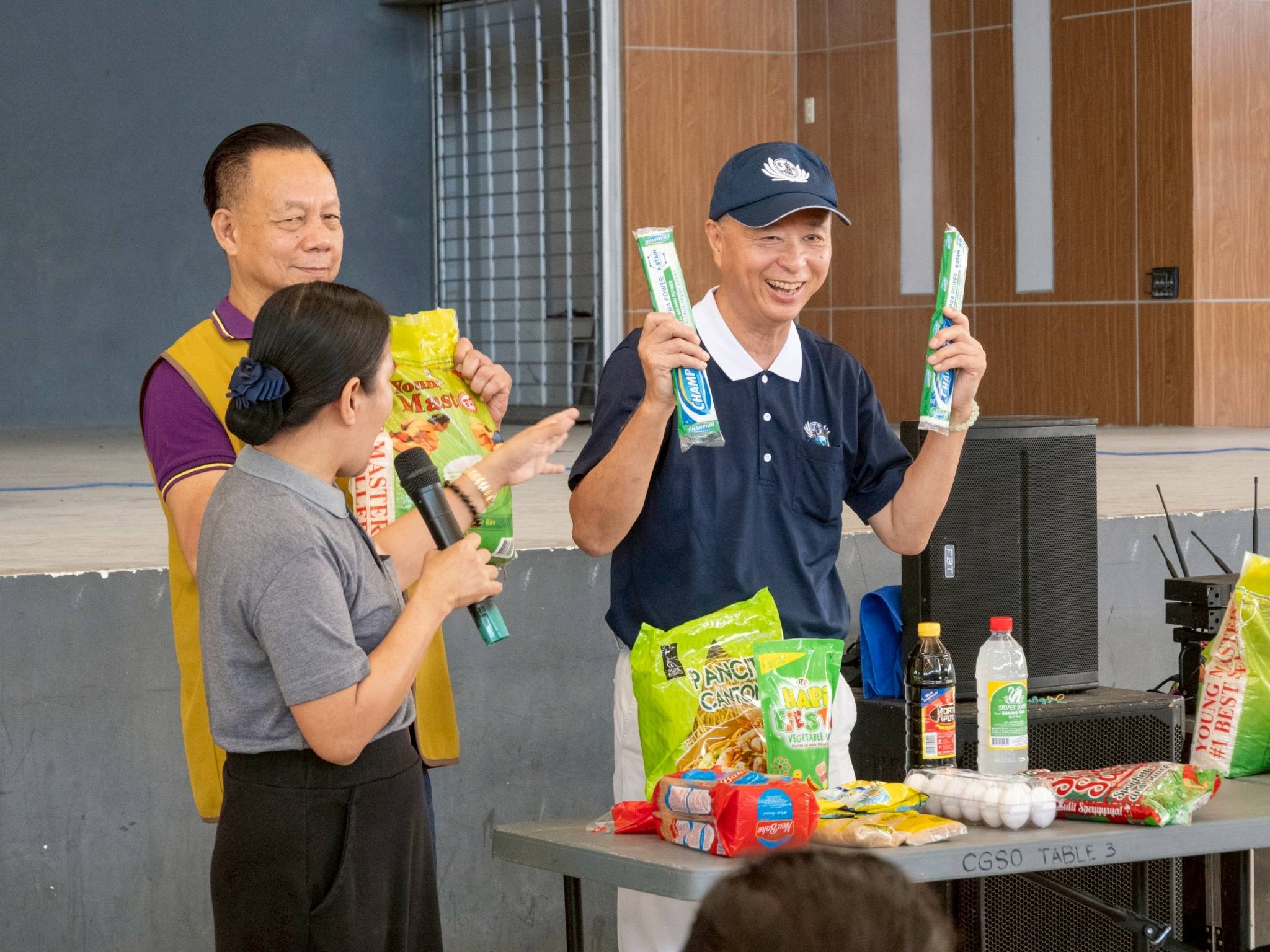 (From left) Tzu Chi staff Julie Collado, Lanao Filipino-Chinese Chamber of Commerce and Industry President James Yu,and Tzu Chi volunteer Luis Diamante show the Iligan beneficiaries examples of items they can buy using their P1,200  grocery gift check.