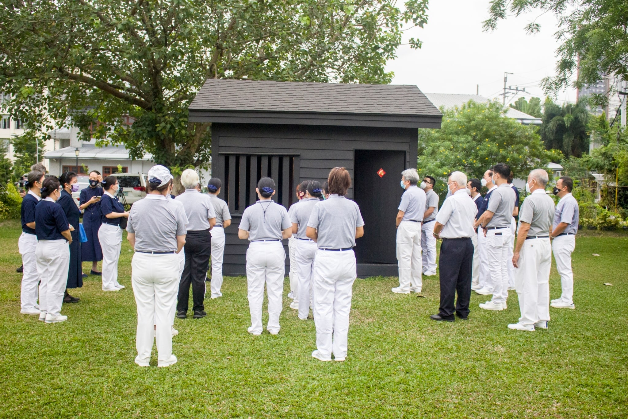 Volunteers in training listen to a speaker explain the significance of the wooden cabin. It’s a replica of the one Dharma Master Cheng Yen lived in during her early years as Tzu Chi founder. 【Photo by Matt Serrano】