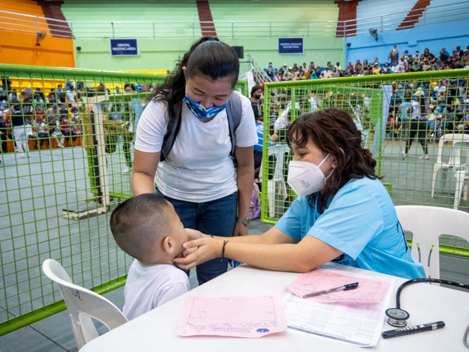 A child is comforted by his guardian as he completes his checkup. 【Photo by Matt Serrano】