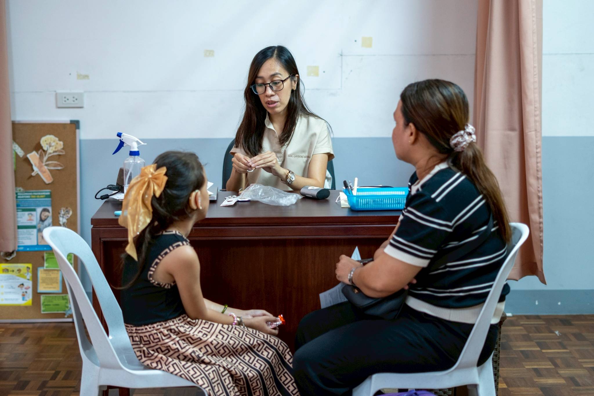 Audiologist Kristine Layson prepares to fit Crystal Cayetano with a hearing aid. 