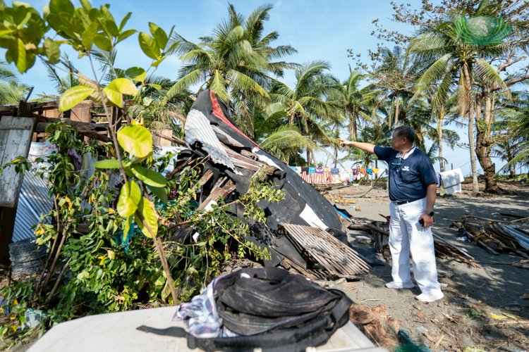 In Ibona, Dingalan, Tzu Chi volunteer Loreto Balete surveys a damaged house whose entrance is blocked by stones. 