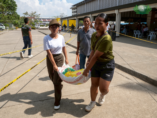 Student volunteers from Sisters of Mary and Talisay City College assist senior citizens by carrying sacks of rice.
