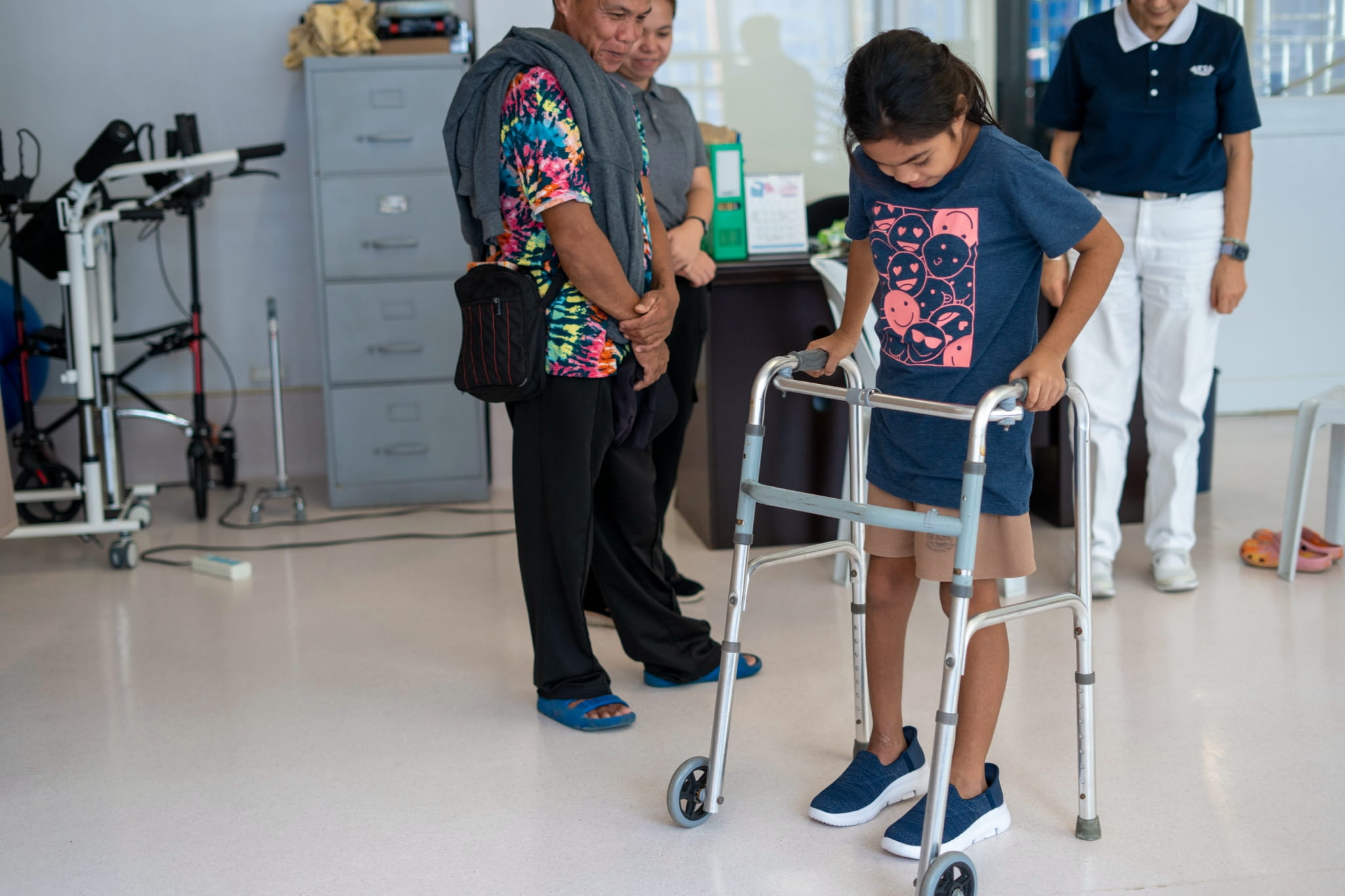 Jamaica Gillado happily tries on her new pair of shoes with a walker for support. 