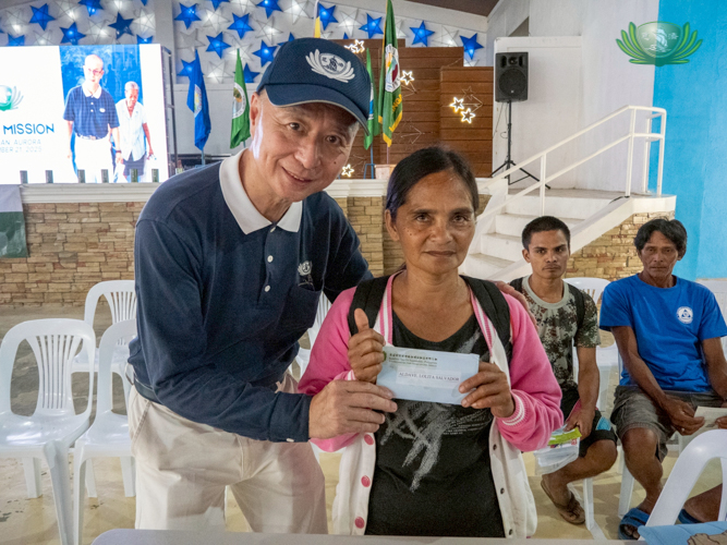 A beneficiary receives cash assistance to help her rebuild her home.