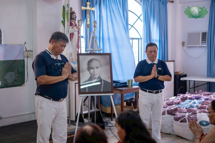 Tzu Chi volunteers Loreto Balete (left) and Benson Lao lead families in a prayer.