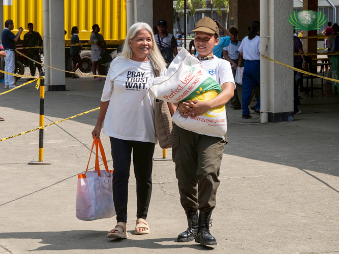 Student volunteers from Sisters of Mary and Talisay City College assist senior citizens by carrying sacks of rice.