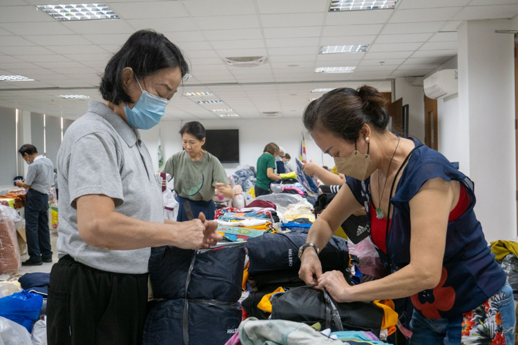 Volunteers neatly secure sets of clothes ready for distribution.