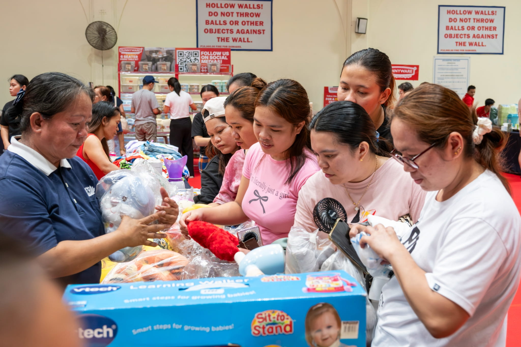 A group of customers happily picks out stuffed toys at the charity bazaar.
