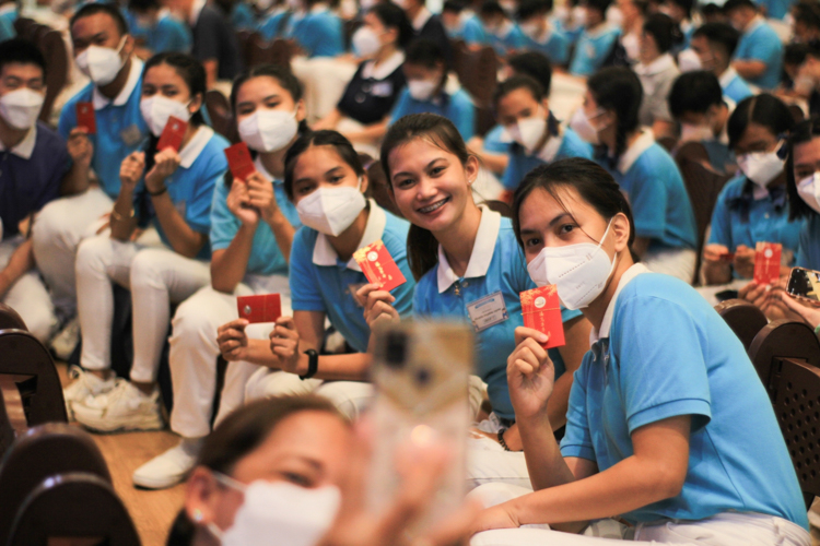 Scholars wave the lucky ampao they received from Dharma Master Cheng Yen. The ampao contains seeds and a commemorative coin.【Photo by Daniel Lazar】