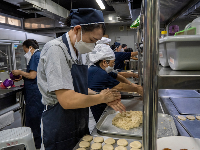 Volunteers tolerate the heat of a hot and crowded kitchen to prepare delicious vegetarian meals for guest.【Photo by Matt Serrano】