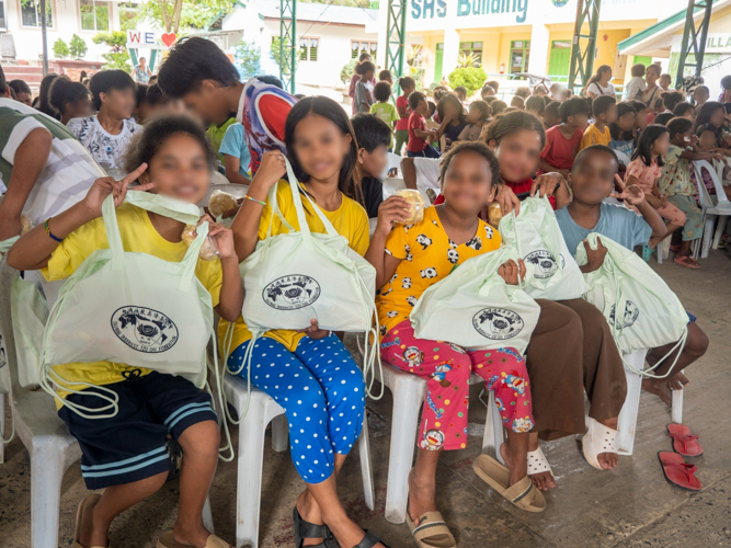 Students show off the school bags they received.